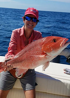 Dr. Morejon, orthodontist at Morejon + Andrews Orthodontics, fishing, holding big red fish on boat in the ocean
