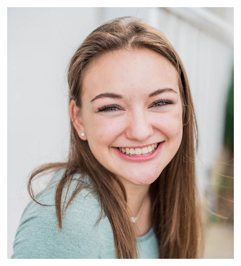 Young teen girl wearing teal shirt and brown hair, smiling at camera with new teeth after orthodontic treatment at Morejon + Andrews Orthodontics